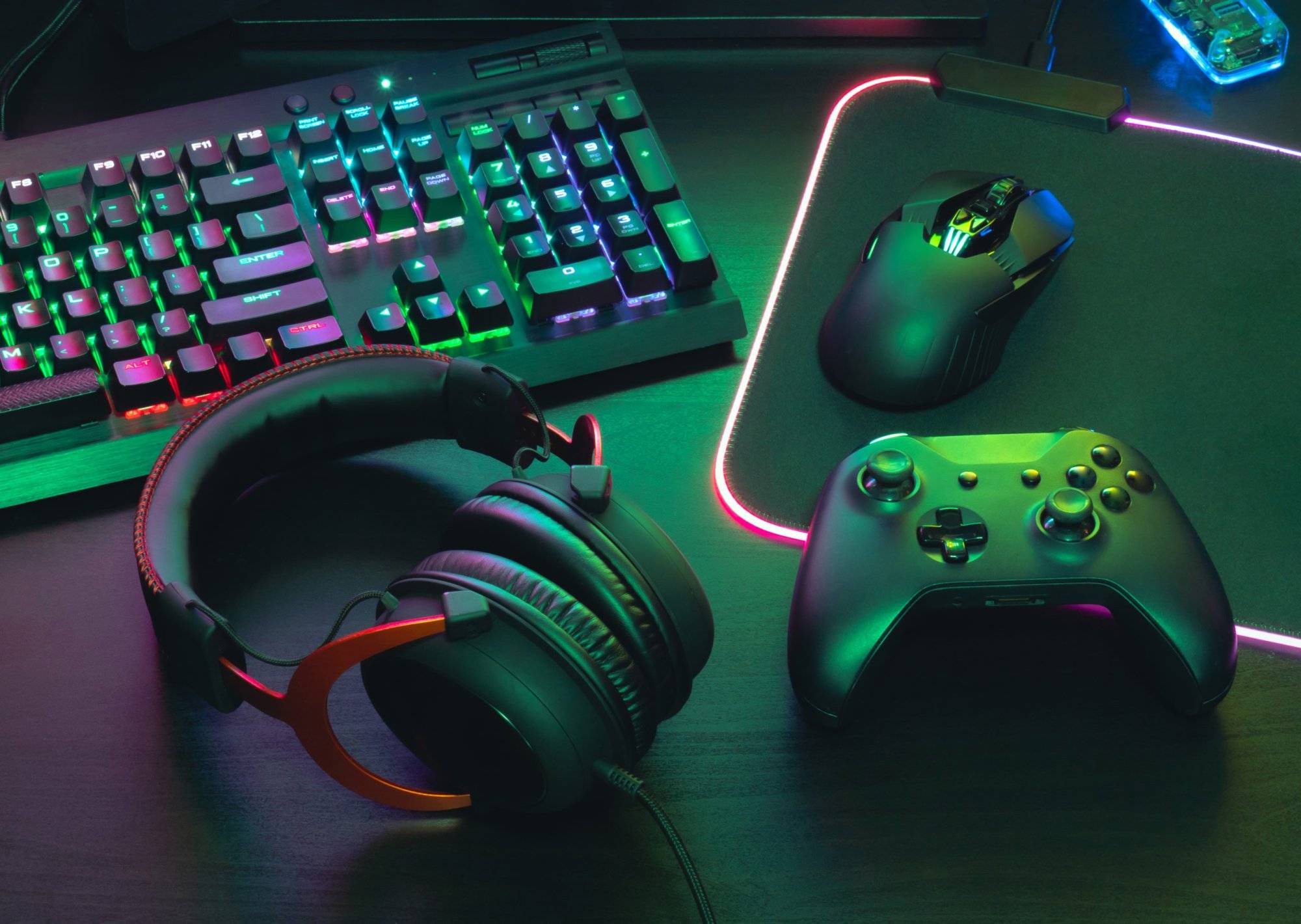 gamer work space concept, top view a gaming gear, mouse, keyboard, joystick, headset, mobile joystick, in ear headphone and mouse pad on black table background.